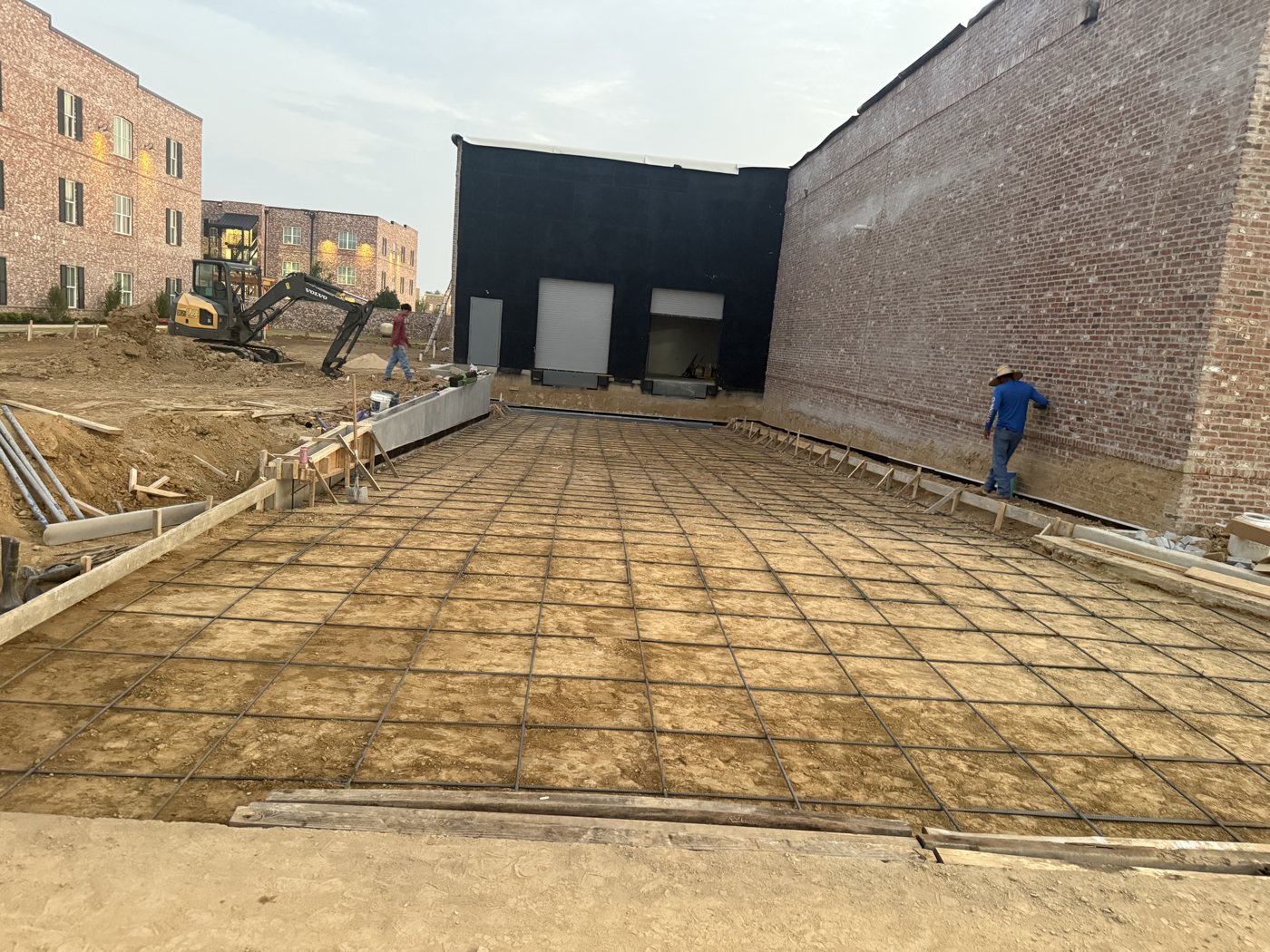 Rebar mat placed for a loading dock apron slab in front of a commercial building's dock doors