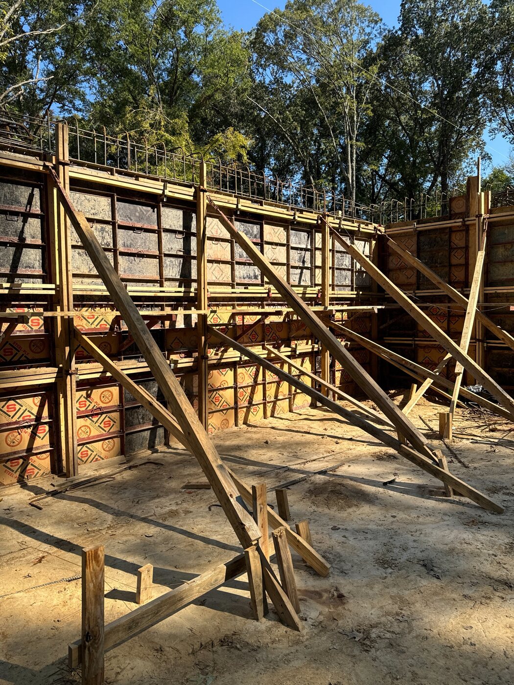 Braced formwork set for a tall reinforced concrete retaining wall pour on a commercial job site